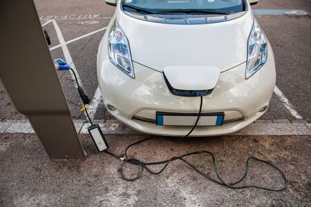 Modern electric car plugged into electricity recharging system stationの写真素材
