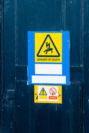 Electrical hazard labels-stickers placed on a fresh blue painted doorの写真素材