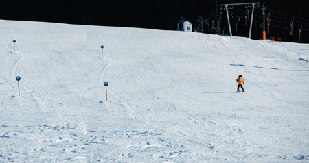 Man skiing down an open slope with trees, signs and ski tracks in the backgroundの写真素材