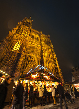 STRASBOURG, FRANCE - NOVEMBER 29, 2014: Full lenght Strasbourg Cathedral with People walking among Christmas stands during the winter Christmas Market on November 29, 2012 in Strasbourg. Strasbourg Christmas Market is considered to be the oldest and the mのeditorial素材