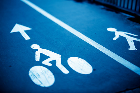 White painted sign for bikes and pedestrian lanes on a blue asphaltの写真素材