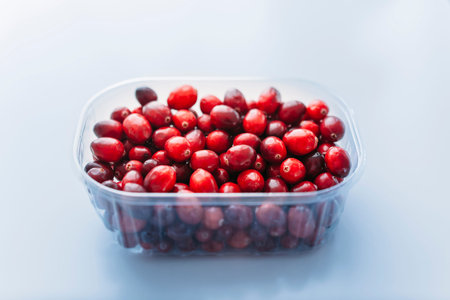 Cranberries in plastic bowl on kitchen background