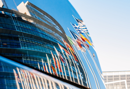 STRASBOURG, FRANCE - JANUARY 28, 2014: European flags and building of the European Parliament reflected in a car windshield parked near to the building. のeditorial素材