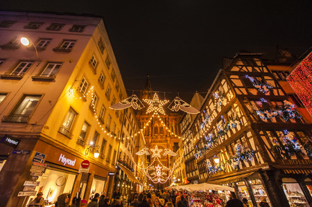 STRASBOURG, FRANCE - NOVEMBER 29, 2014: Full lenght Strasbourg Cathedral with People walking through Rue Merciere and Christmas stands during the winter Christmas Market on November 29, 2012 in Strasbourg. Strasbourg Christmas Market is the oldest and theのeditorial素材