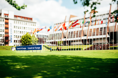 STRASBOURG, FRANCE - June 01, 2012: Building of Parliamentary Assembly of the Council of Europe with flags and turist photographing near them on June 01, 2012. Tilt-shift lens used for better accent name of the institutionのeditorial素材