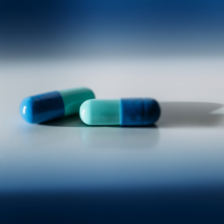 Blue green pills on doctors table. Tilt-shift lens used to outline the drugs and to emphasize the attention on themの写真素材