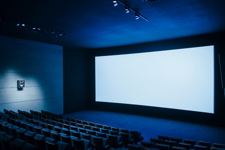 Cinema auditorium with white screen and luxury seats - dark movie theatre ready for projectionのeditorial素材