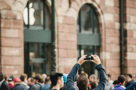 STRASBOURG, FRANCE - SEPTEMBER 19, 2014: A young man takes a picture of the crowd in front of the Apple Store as people enter on the first day of sales of the new Apple iPhone 6.  Apple stores attracted long lines of fans and shoppers for the debut of theのeditorial素材