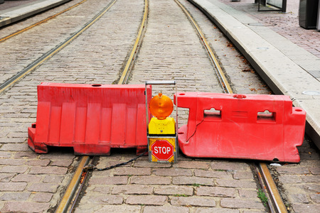 Road closed STOP sign and two red symbol barrier over a tramway track.の写真素材