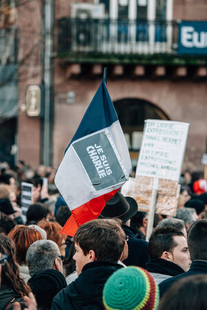 STRASBOURG, FRANCE - 11 JAN, 2015:  People hold placards reading 'Je suis Charlie' on a French flag during a unity rally (Marche Republicaine) where some 50000 people took part in tribute three-day killing spree in Parisのeditorial素材
