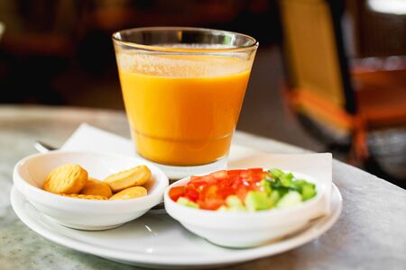 Japanese pumpkin orange soup served in bowl on table with salad and breadの写真素材