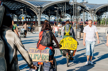 COLOGNE, GERMANY - JUNE 3, 2010: Two cyclists militation against the CO2 producing and climate change passing through tourists and visitors of Cologne in the  Domplatte square in front of the KÃ¶lner Domのeditorial素材