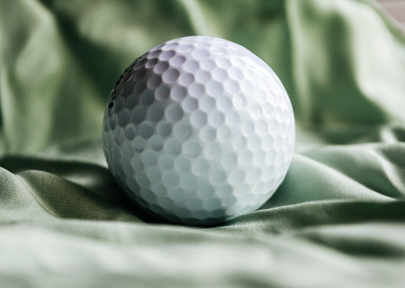Golf ball on green silk textile background. Depicting luxury quality of golf communityの写真素材