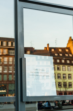 Apple Store with working and covered shopping windows and message in French for delays in working hours during Apple Watch launch weekのeditorial素材