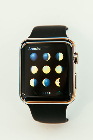 PARIS, FRANCE â APR 10, 2015: New wearable computer Apple Watch smartwatch displaying the new moon Phases Emoji. Apple Watch incorporates fitness tracking and health-oriented capabilities and  integration with iOS Apple products and servicesのeditorial素材