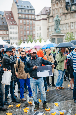 STRASBOURG, FRANCE - APR 26 2015: I am a migrant poster holed by a man at protest against immigration policy and border management which asks for commitment in the wake of migrants boat disastersのeditorial素材