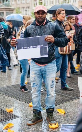 STRASBOURG, FRANCE - APR 26 2015: I am a migrant poster holed by a man at protest against immigration policy and border management which asks for commitment in the wake of migrants boat disastersのeditorial素材