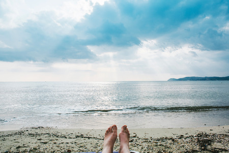 Close up of female legs and feet sunbathing on beachの写真素材