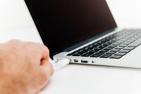 PARIS, FRANCE - FEBRUARY 13, 2015: Hand connectiong thudnerbolt cable to modern laptop computer with thuderbolt portの写真素材
