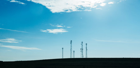 Five telecommunication mast TV antennas with blue sky and white clouds in the morning