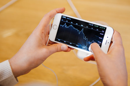 PARIS, FRANCE - OCT 3, 2015: Customer checks the new iPhone 6s Plus displayed at the Apple Store Opera with the Apple Stock App checking financial quotationsのeditorial素材