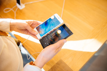 PARIS, FRANCE - OCT 3, 2015: Woman comparing the new iPhone 6s with Microsoft Lumia phone during the sales launch of the latest Apple Inc. smartphonesのeditorial素材