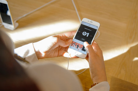 PARIS, FRANCE - OCT 3, 2015: Woman checks the new iPhone 6s displaying the new Beats 1 radio