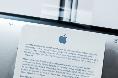 PARIS, FRANCE - JANUARY 14, 2015: New Apple Macbook Pro Retina laptop unboxing security seal with important notice about software agreementのeditorial素材