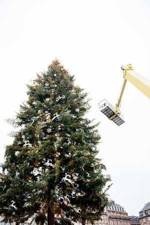Christmas xmas tree assemblage by crane and workers in modern city - Franceの写真素材