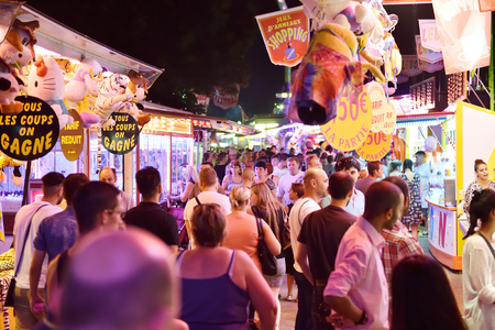 STRASBOURG, FRANCE - JULY 19, 2015: Crowd of people late night in amusement park admiring diverse offersのeditorial素材
