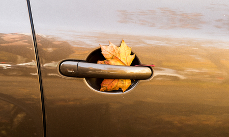 Yellow leaf in car door - fall is comingの写真素材