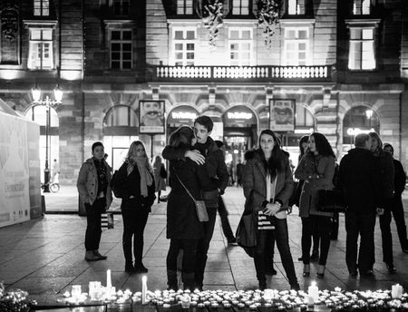 STRASBOURG, FRANCE - 14 NOV 2015: Sad couple and other people looking at candles in the center of Strasbourg for the victims of the November 13 attacks in Paris that killed at least 128 peopleのeditorial素材
