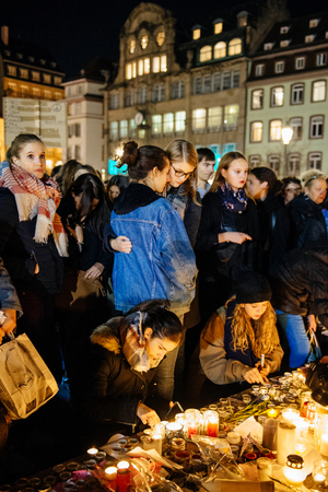 STRASBOURG, FRANCE - NOV 18, 2015: Embracing of two friends near flowers, messages and candles in center of Strasbourg, in solidarity for victims and families of the assault in Parisのeditorial素材