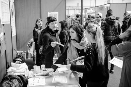 STRASBOURG, FRANCE - FEB 4, 2016: Children and teens of all ages attending annual Education Fair to choose career path and receive vocational counseling - young girls getting a flyerのeditorial素材