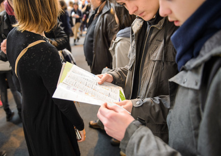STRASBOURG, FRANCE - FEB 4, 2016: Children and teens of all ages attending annual Education Fair to choose career path and receive vocational counseling - bous reading flyerのeditorial素材