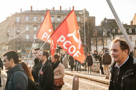 STRASBOURG, FRANCE - FEB 6, 2016: Communist flags in hands of protesters marching during a demonstration against government's plan to extent the 'state of emergency' and for opened bordersのeditorial素材