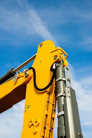 Hydraulic excavator arm - industrial equipment as seen on construction site agains beautiful blue skyの写真素材