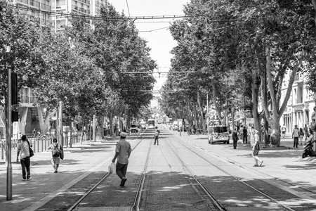 MARSEILLE, FRANCE - JUL 18, 2014: Black and white image of Cours Belsunce main boulevard with people walking on pedestrian street, tourists admiring the city and the Triumphal Arch of Port d'Aix in the bacgroundのeditorial素材