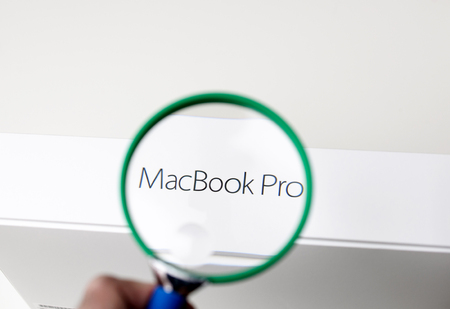 PARIS, FRANCE - JANUARY 14, 2015: Man looking through a magnifying glass to the MacBook Pro computer laptop box signのeditorial素材