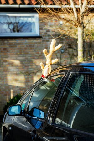 Toy deer antlers on a parked car in front of the houseの写真素材