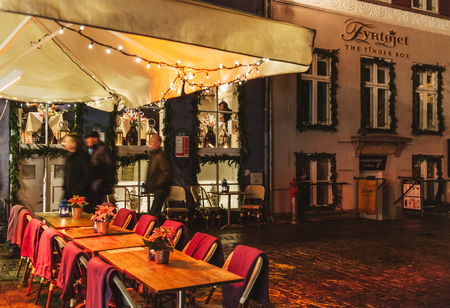 Copenhagen, Denmark - December 27, 2014: Group of friend passing near empty terrase near the famous Fyrtojet restaurant on the border of Nyhavn canal at night, Copenhagen, Denmarkのeditorial素材
