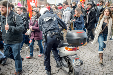 STRASBOURG, FRANCE - 9 MAR 2016 Police officer in the middle of the crowd as thousands of people demonstrate as part of nationwide day of protest against proposed labor reforms by Socialist Governmentのeditorial素材