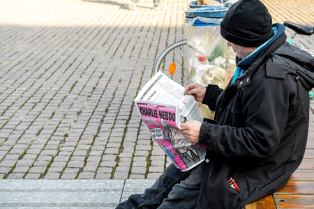 STRASBOURG, FRANCE - 9 MAR 2016:  Man reading satirical magazine Charlie Hebdo in Place Kleber, Strasbourg France, Alsaceのeditorial素材
