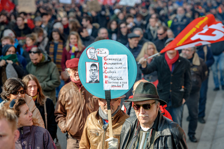 STRASBOURG, FRANCE - 9 MAR 2016: Man holding anti left wing placard  as thousands of people demonstrate as part of nationwide day of protest against proposed labor reforms by Socialist Governmentのeditorial素材