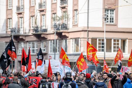 STRASBOURG, FRANCE - 9 MAR 2016: Communist flags waving as thousands of people demonstrate as part of nationwide day of protest against proposed labor reforms by Socialist Governmentのeditorial素材