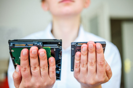 IT specialist hands holding fast flash SSD - solid state drive and Hard Drive Disk HDDの写真素材
