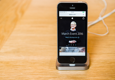 STRASBOURG, FRANCE - APR 9, 2016: New iPhone SE in docking station with Apple.com marhc event page opened. New Apple iPhone tends to become one of the most popular smart phones in the world.のeditorial素材