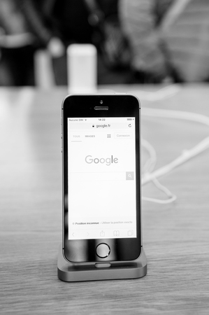 STRASBOURG, FRANCE - APR 9, 2016: New iPhone SE in docking station with Google search engine page opened. New Apple iPhone tends to become one of the most popular smart phones in the world.のeditorial素材