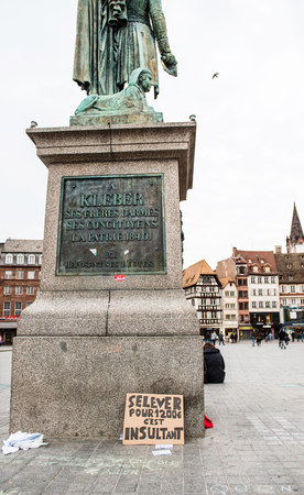 STRASBOURG, FRANCE - APR 9, 2016: French placard on General Kleber statue reading "Waking up for 1200 Euro is insulting" during public placard drawings in Place Kleberのeditorial素材