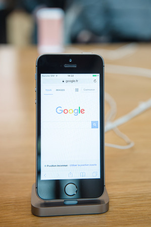 STRASBOURG, FRANCE - APR 9, 2016: New iPhone SE in docking station with Google search engine page opened. New Apple iPhone tends to become one of the most popular smart phones in the world.のeditorial素材